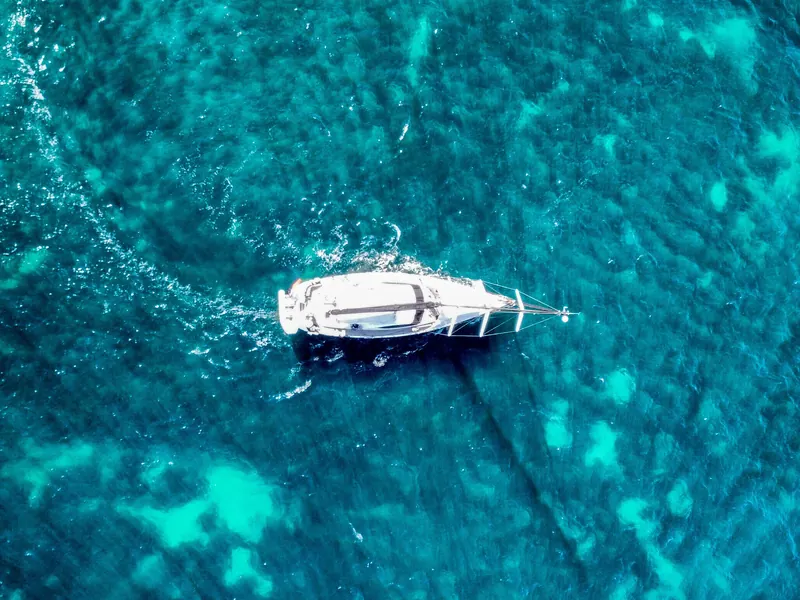 Vista aérea de un velero navegando en aguas abiertas de color turquesa